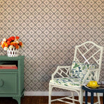a white chair in front of a navy bamboo trellis wallpaper design on a white background from Madcap Cottage. 