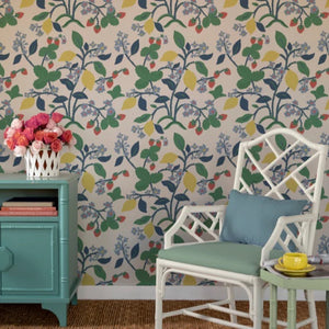 A white chair and blue sideboard against a background of lemon and strawberry wallpaper