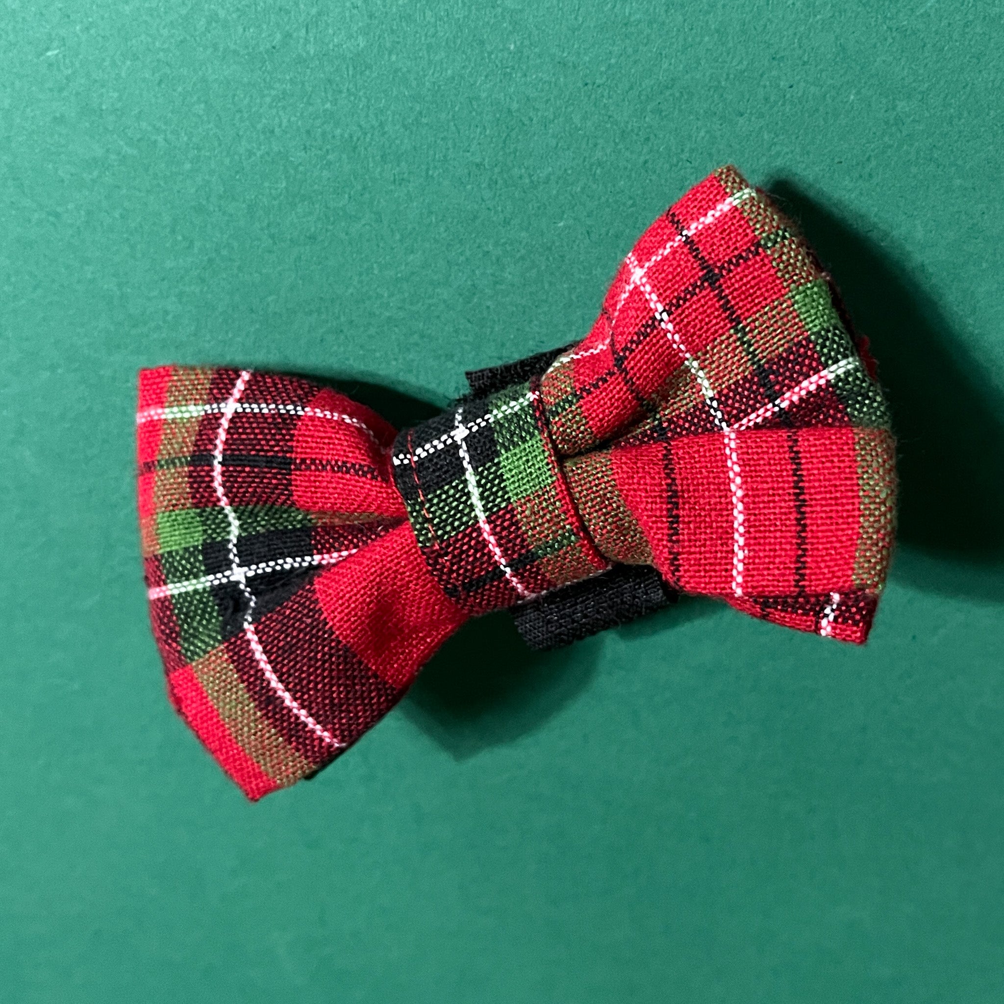 a Royal Stewart Red/Green Plaid Dog/Cat Bowties placed on a green surface