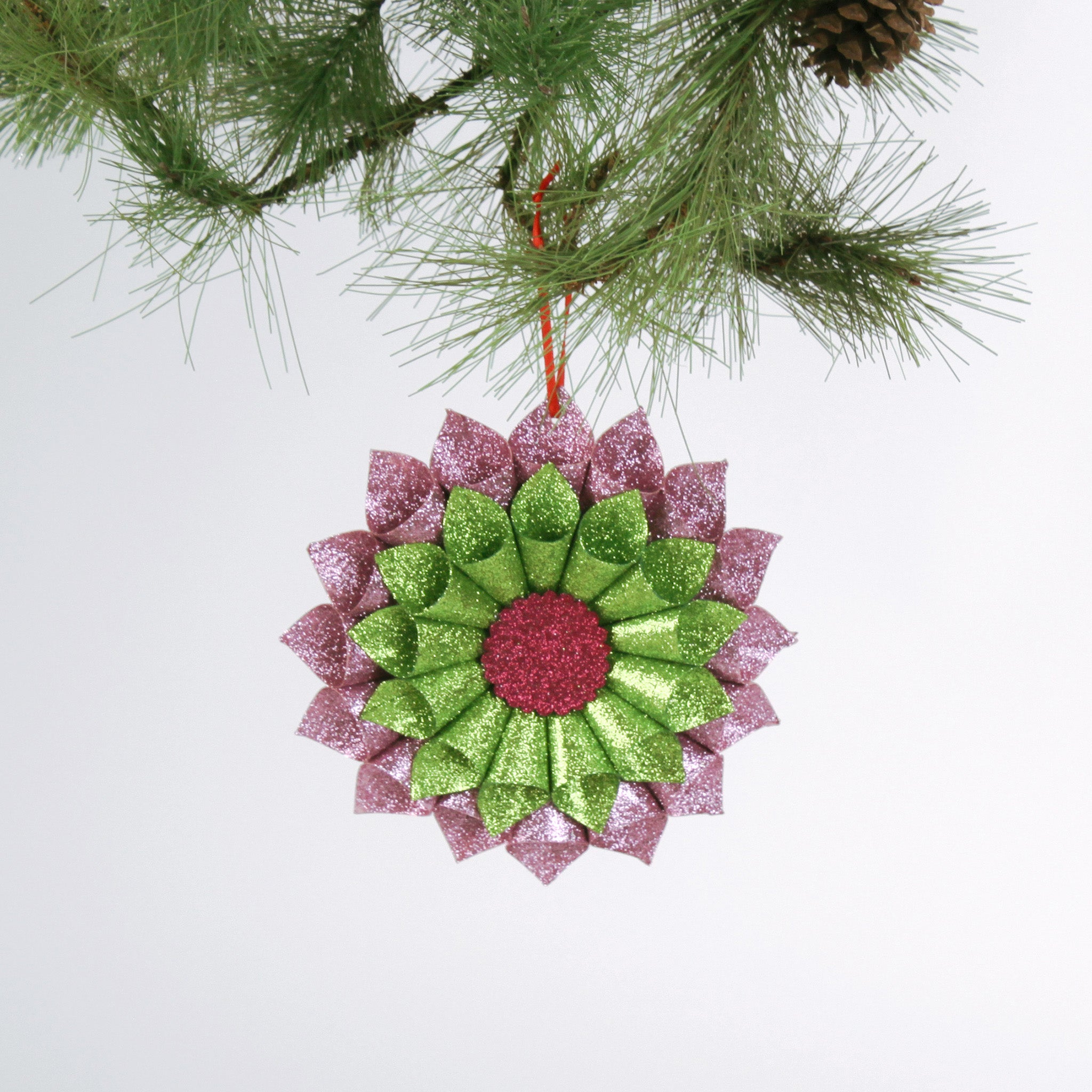 ruffled paper Christmas ornaments in shimmering green and purple glitter with red centers