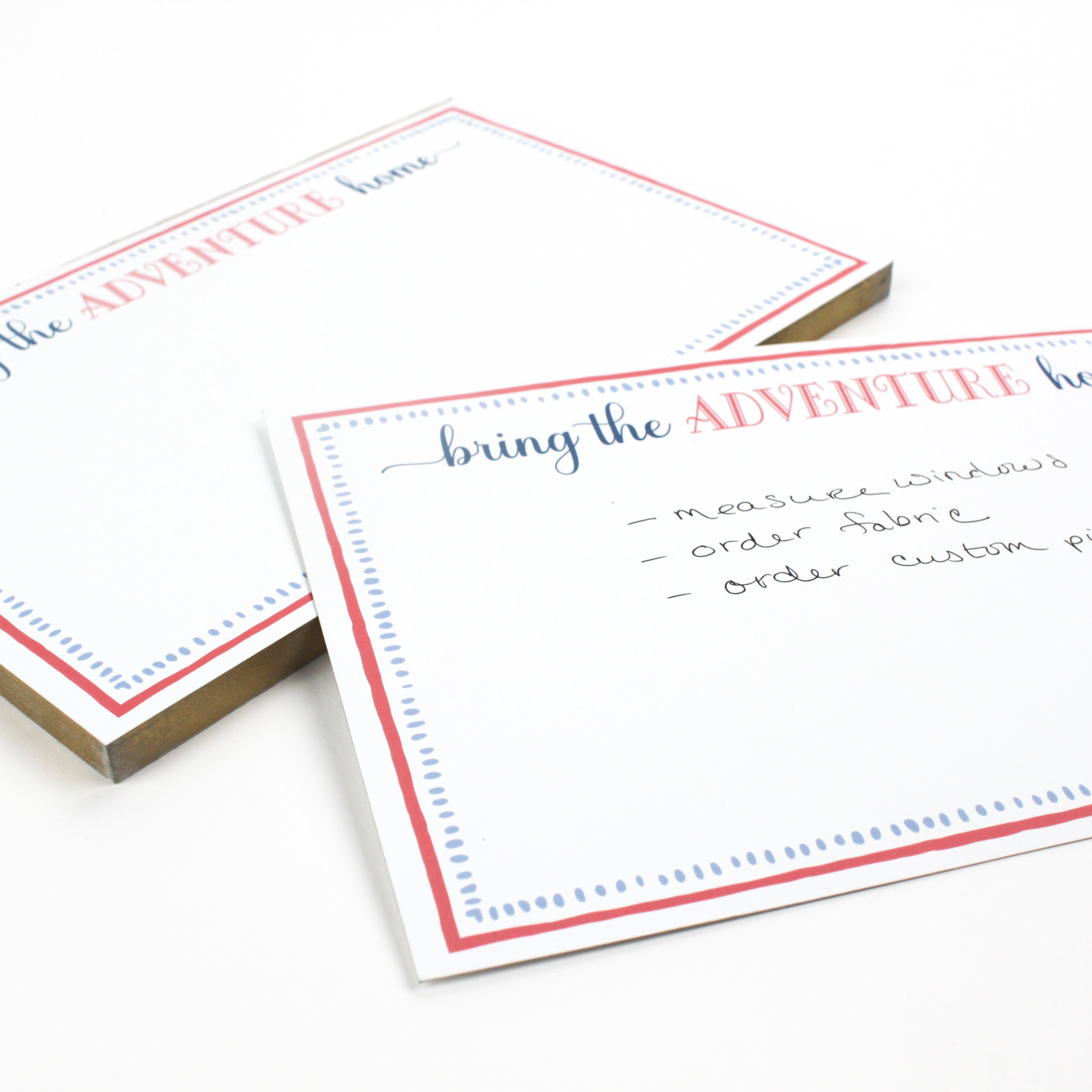 Luxe large notepad with quote ‘Bring the Adventure Home’ in blue and red typography, bordered with dotted design for chic desk stationery. placed in a white background