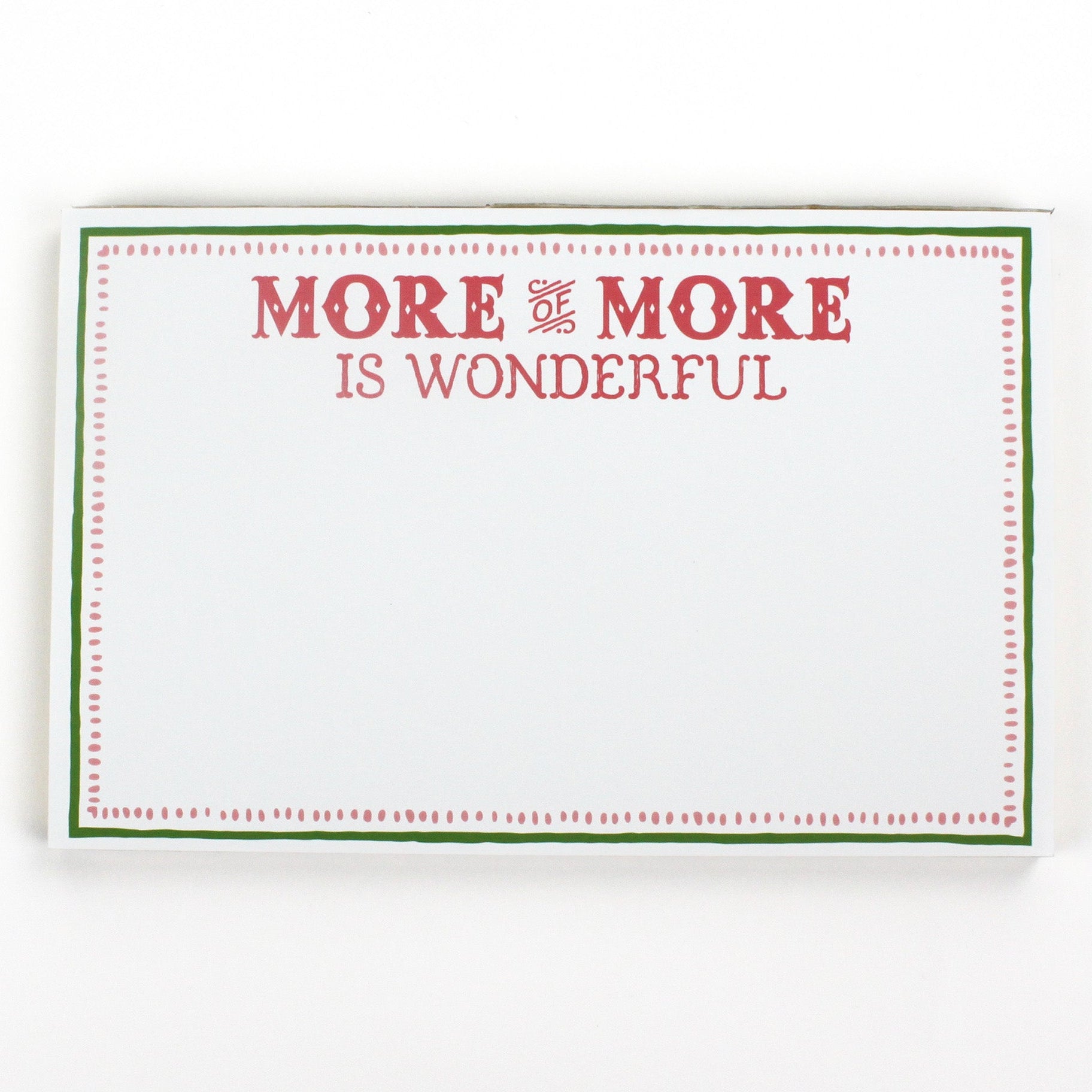 Luxe large notepad with quote ‘More of More is Wonderful’ in red lettering, featuring a dotted border and green trim, perfect for stylish note-taking. placed in a white background