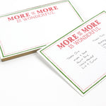 Luxe large notepad with quote ‘More of More is Wonderful’ in red lettering, featuring a dotted border and green trim, perfect for stylish note-taking. placed in a white background