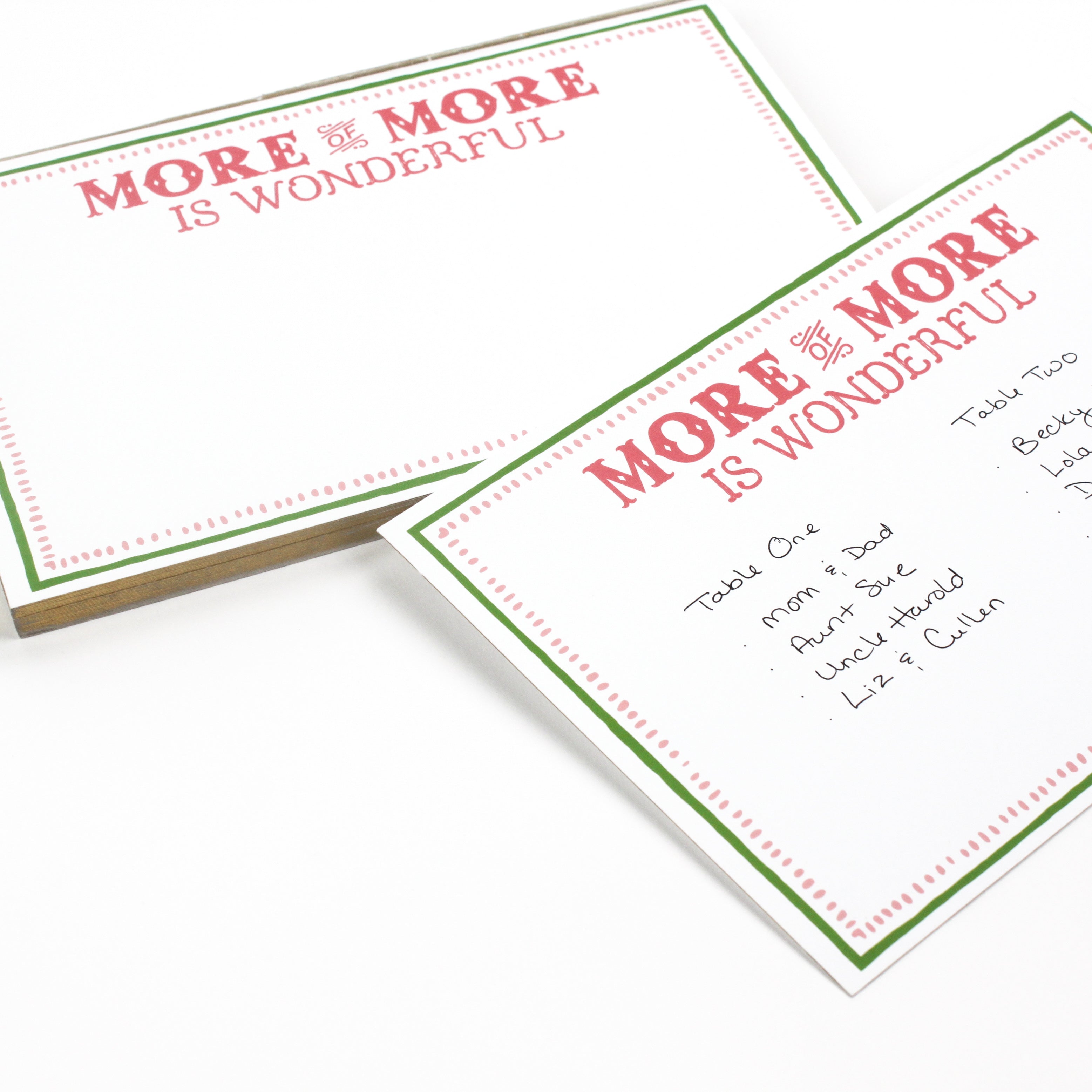 Luxe large notepad with quote ‘More of More is Wonderful’ in red lettering, featuring a dotted border and green trim, perfect for stylish note-taking. placed in a white background