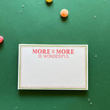 Luxe large notepad with quote ‘More of More is Wonderful’ in red lettering, featuring a dotted border and green trim, perfect for stylish note-taking. placed in a green background