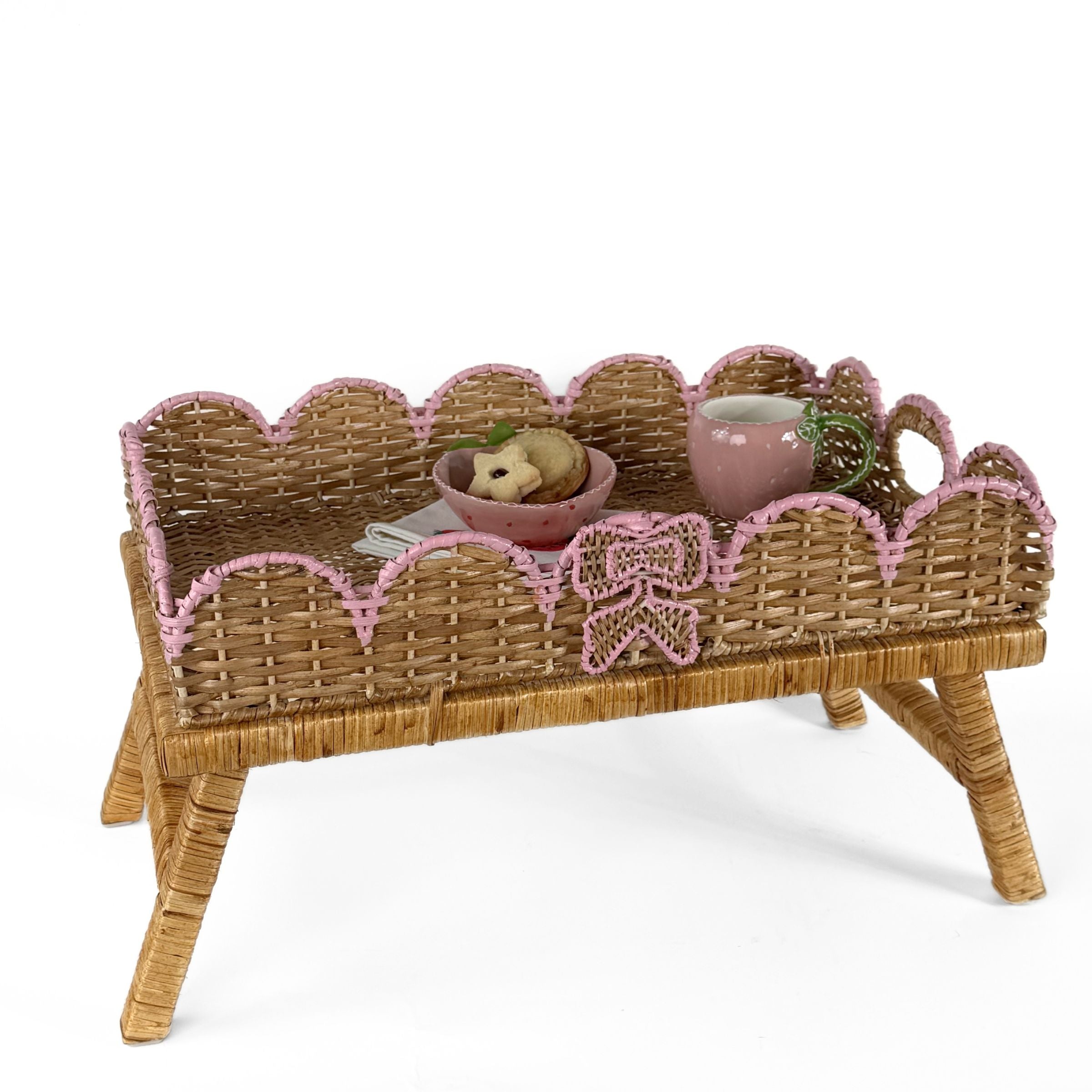 Scalloped hand-painted pink rattan tray styled with cookies, teacup, and decorative ribbon detail.