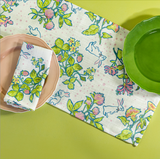 a table set with a bunny and strawberry print fabric easter table runner, napkins and plates. 