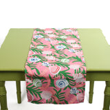 Pink and green table runner featuring colorful seashell patterns laid across a green table.