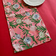 Shell Seekers cloth Table Runner features colorful shells, pink ribbons and green foliage on a pink background