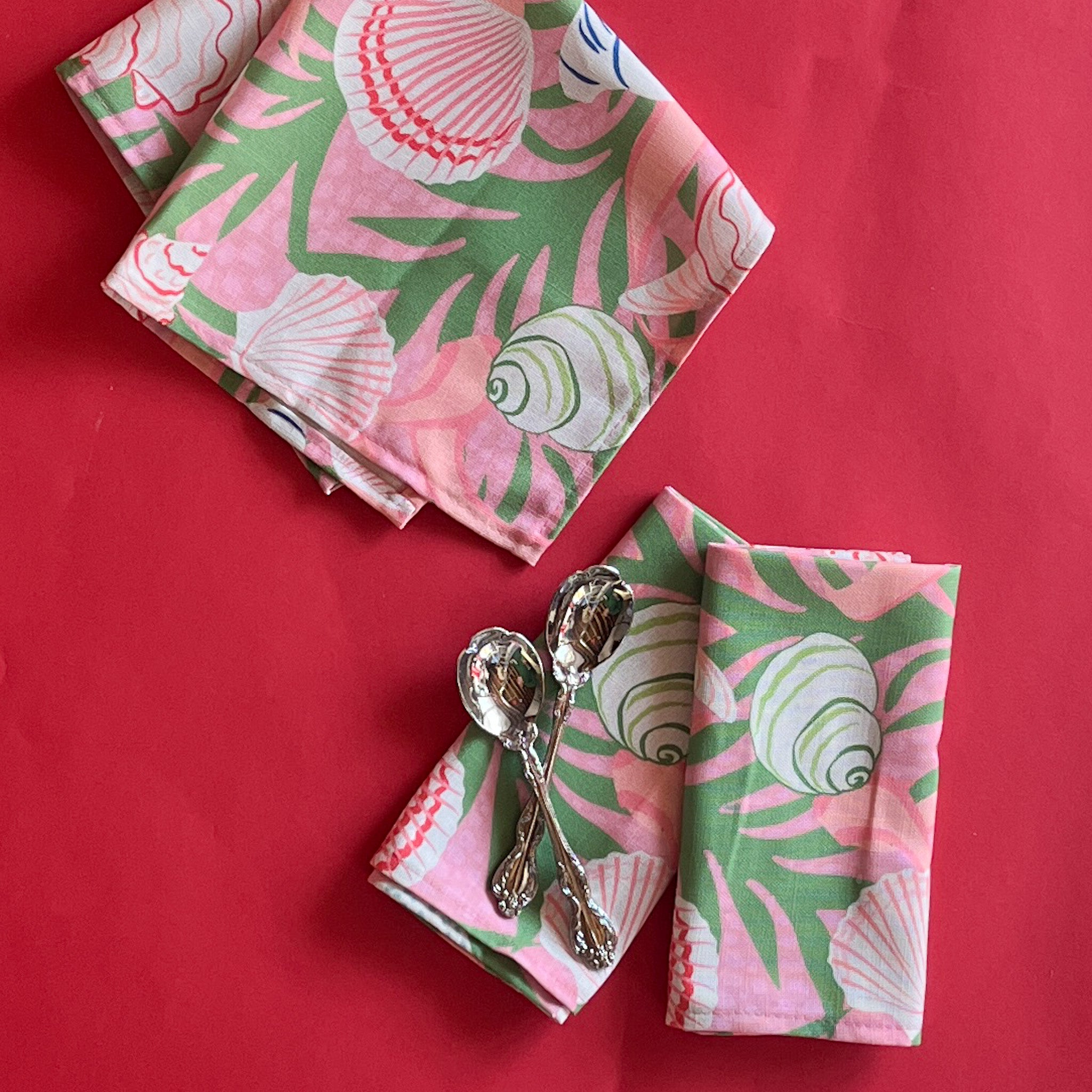 Shell Seekers pink and green napkins with a shell and seaweed pattern folded with two silver spoons