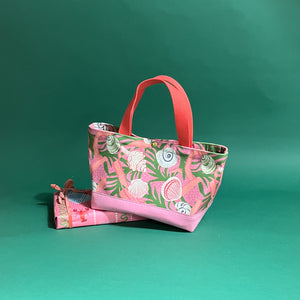 Small Shell Seekers canvas tote bag with pink fabric with a repeating seaweed and shell motif resting on a present.