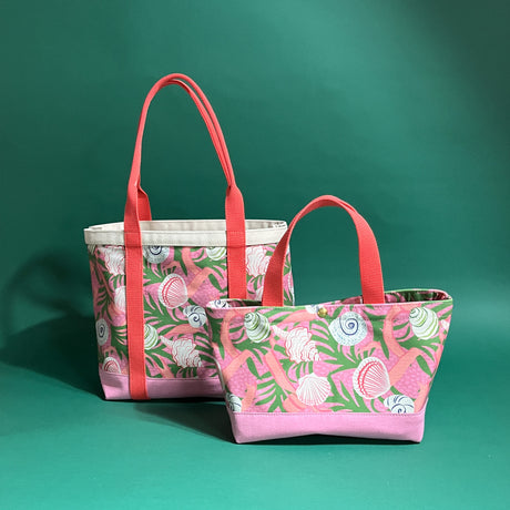 Shell Seekers canvas tote bags with pink fabric with a repeating seaweed and shell motif.