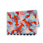Folded Shells and Lobsters cotton tea towel featuring bright red lobsters and colorful seashells on a light blue background.