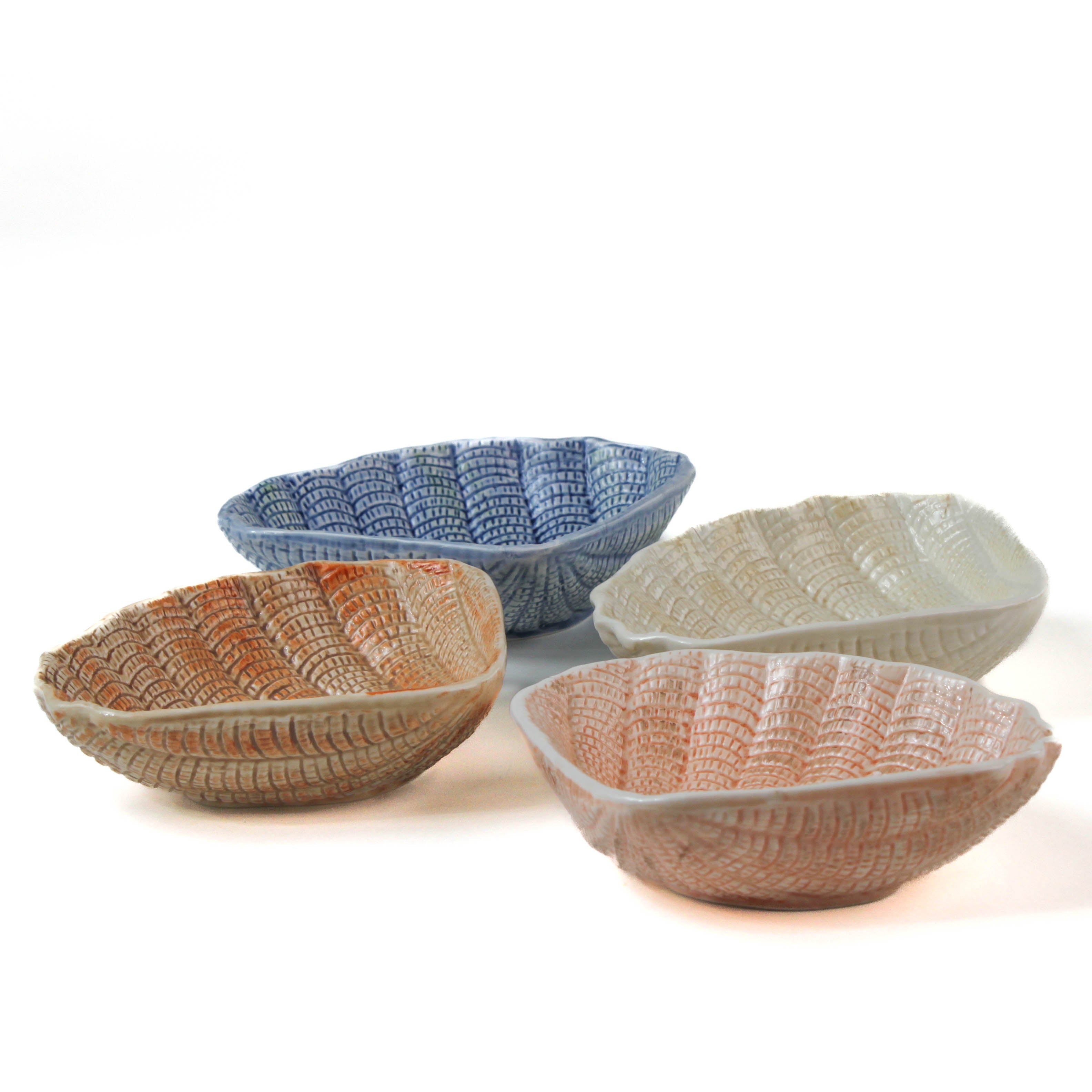 a small ceramic shell bowl set featuring four shells in blue, brown, pink and white