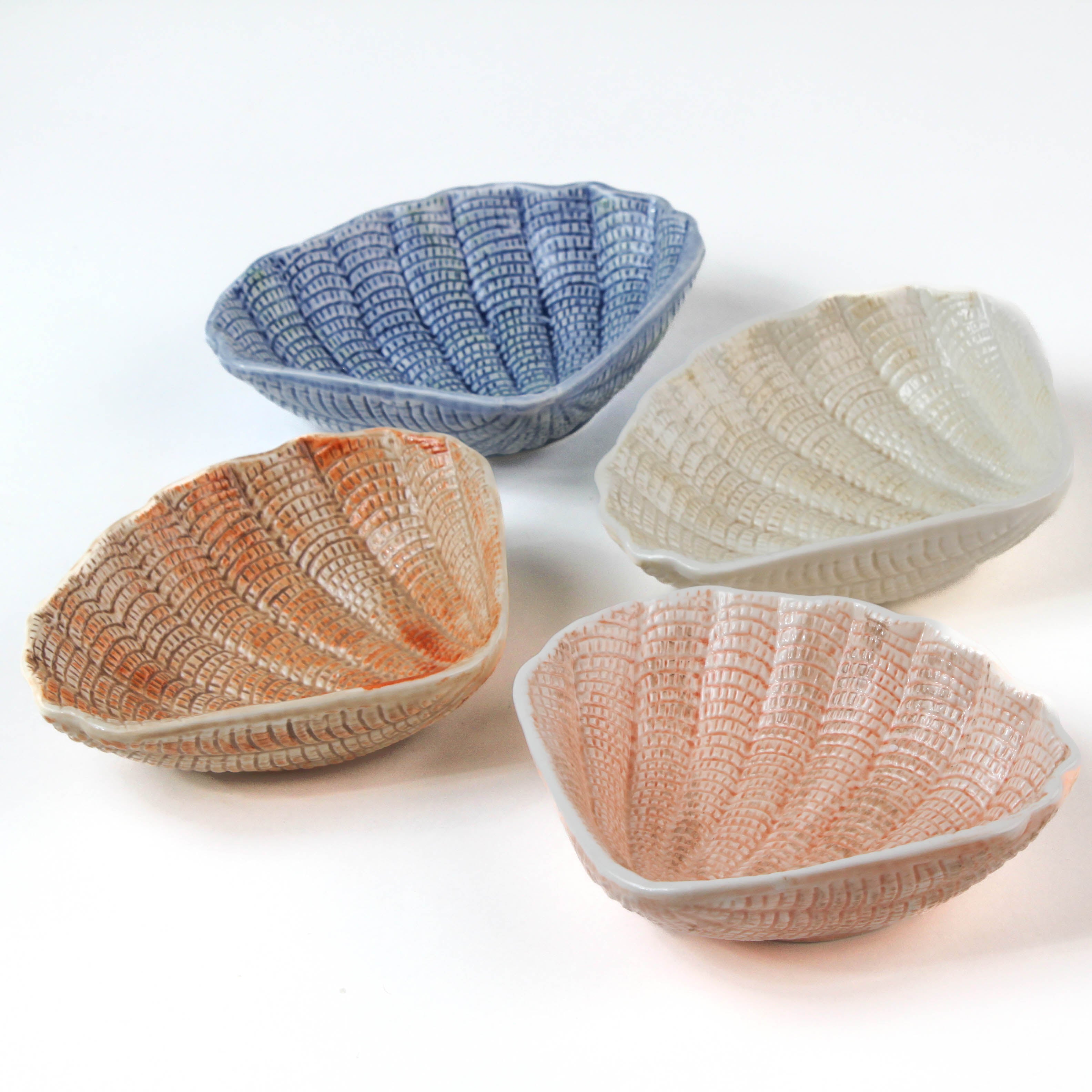 a small ceramic shell bowl set featuring four shells in blue, brown, pink and white