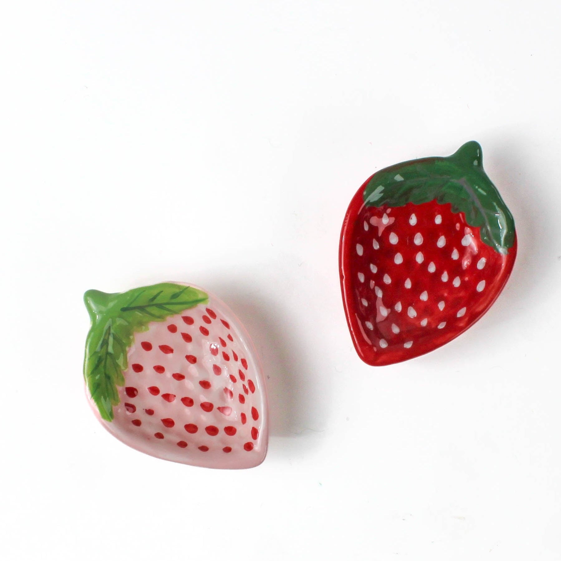 pink and red ceramic strawberry bowls on a white background