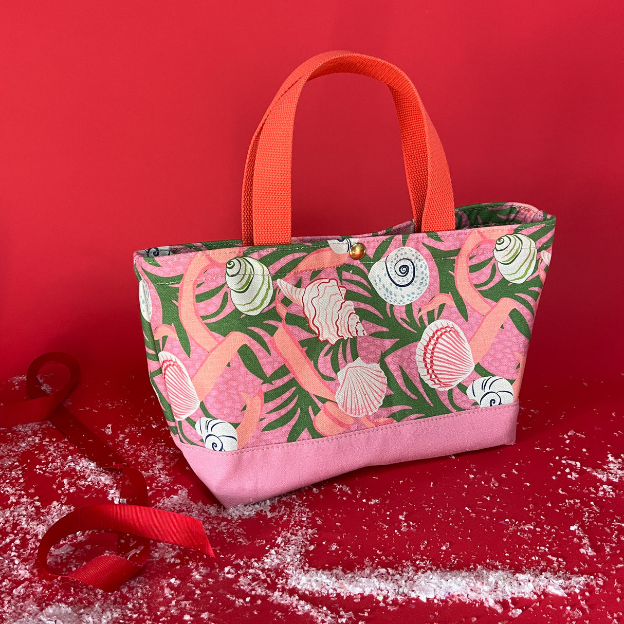 Small Shell Seekers canvas tote bag with pink fabric with a repeating seaweed and shell motif.