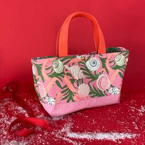 Small Shell Seekers canvas tote bag with pink fabric with a repeating seaweed and shell motif.