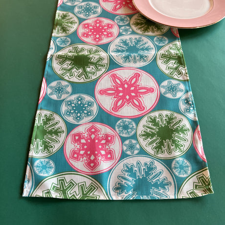 Snowflake Wonderland Christmas Cloth Table Runner on a green background