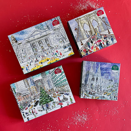 Four packaged jigsaw puzzles depicting snowy scenes of New York City, including St. Patrick's Cathedral, the Brooklyn Bridge, and the New York Public Library.