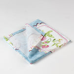 folded cloth napkins featuring a blue background with vintage floral plate designs.