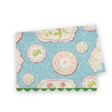 Folded Society Hill Painted Plates cotton tea towel featuring decorative floral plates on a soft blue background with green scalloped trim.