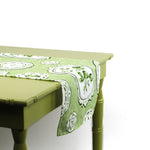 Side view of a green and white patterned table runner draped over a green table.