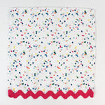 Cloth napkin laid flat with multicolor confetti dots and pink scalloped trim.