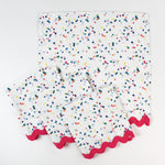 Set of cloth napkins with a colorful confetti dot pattern and pink scalloped trim.
