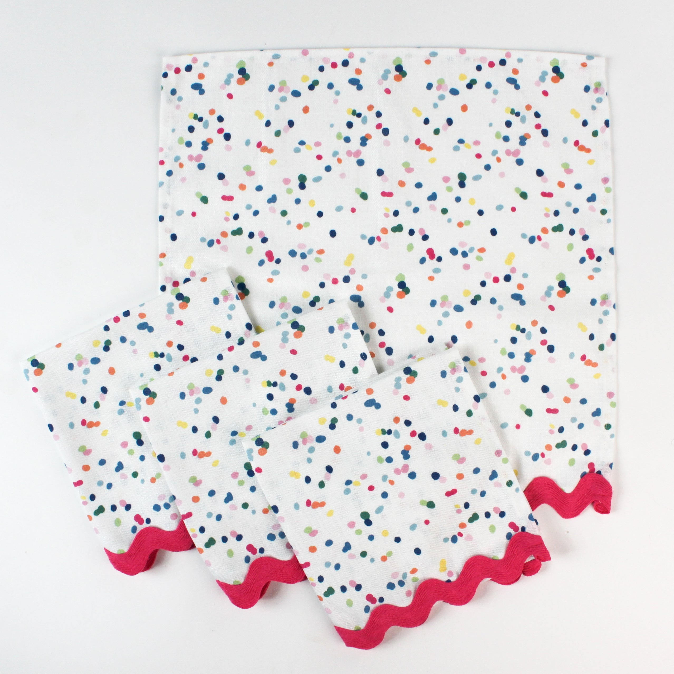 Set of cloth napkins with a colorful confetti dot pattern and pink scalloped trim.