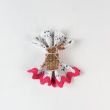 Confetti-print cloth napkin styled with a woven bunny napkin ring and pink scalloped trim.