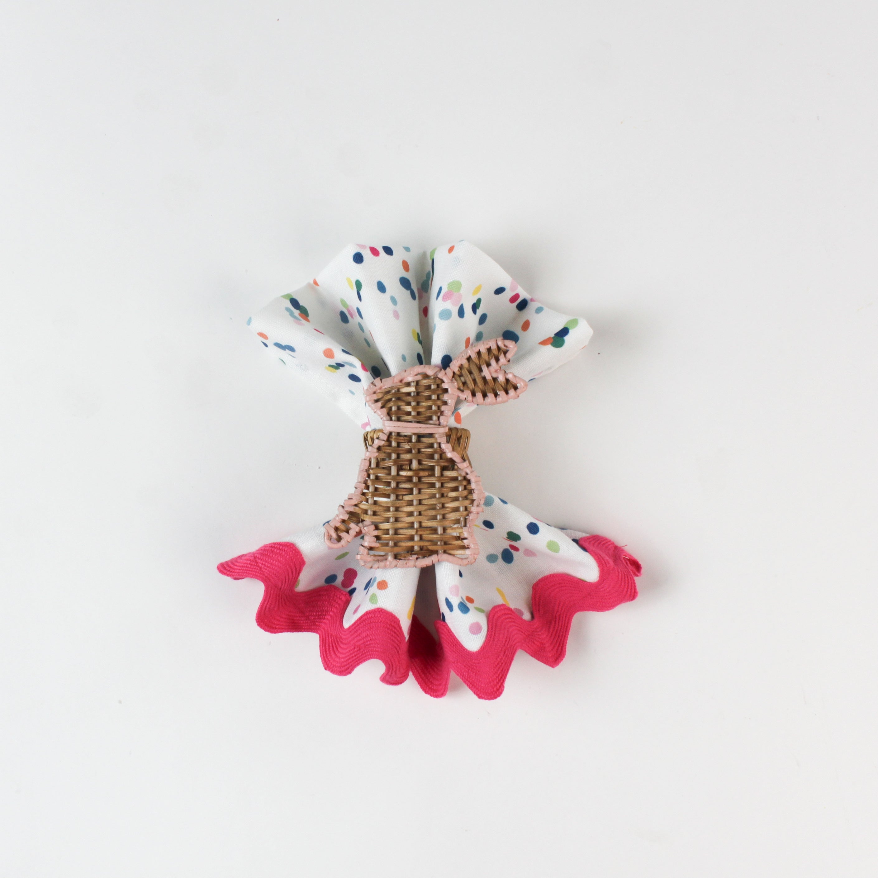 Confetti-print cloth napkin styled with a woven bunny napkin ring and pink scalloped trim.