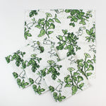 Set of cloth napkins with a green botanical and bunny print laid out together.