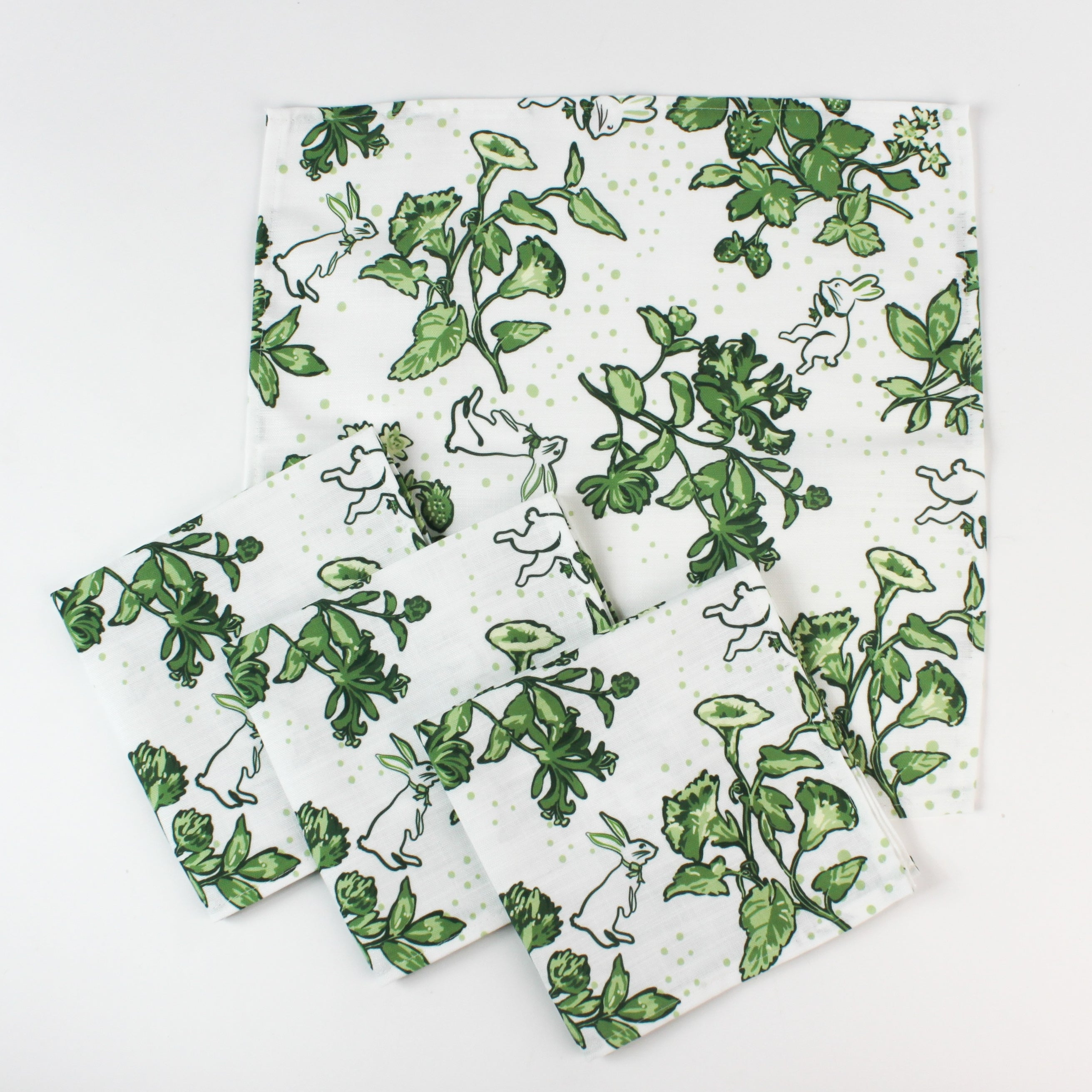 Set of cloth napkins with a green botanical and bunny print laid out together.