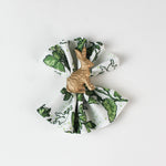 Green botanical patterned cloth napkin styled with a gold rabbit napkin ring.
