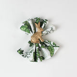 Green botanical patterned cloth napkin styled with a gold rabbit napkin ring.