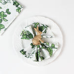 Green botanical  in white plate patterned cloth napkin styled with a gold rabbit napkin ring.