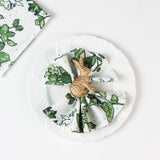 Green botanical  in white plate patterned cloth napkin styled with a gold rabbit napkin ring.