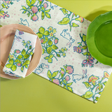 a table set with a Springtime Strawberry print cloth table runner, napkins and plates. 