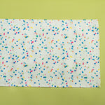 A Springtime confetti print cloth table runner on a light green background