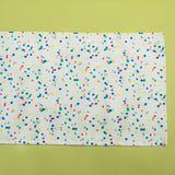 A Springtime confetti print cloth table runner on a light green background