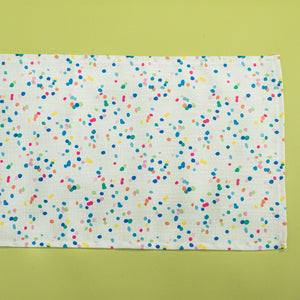 A Springtime confetti print cloth table runner on a light green background
