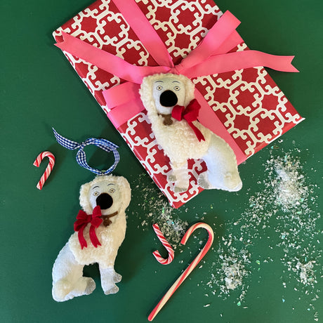 Two hand-crafted felt Staffordshire dog christmas ornamentswith red bows and candy cane decorations, set against a patterned background.