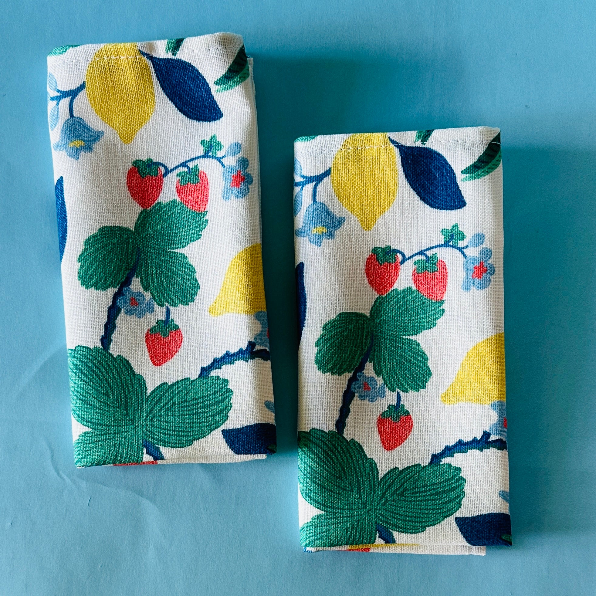 Set of two Strawberry Hill cloth dinner napkins on a blue background