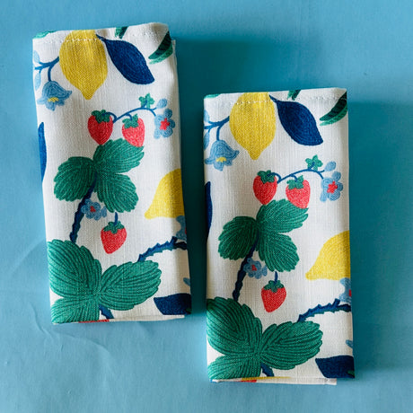 Set of two Strawberry Hill cloth dinner napkins on a blue background