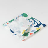 Close-up of folded cloth napkin showing floral, strawberry, and lemon print on white fabric.