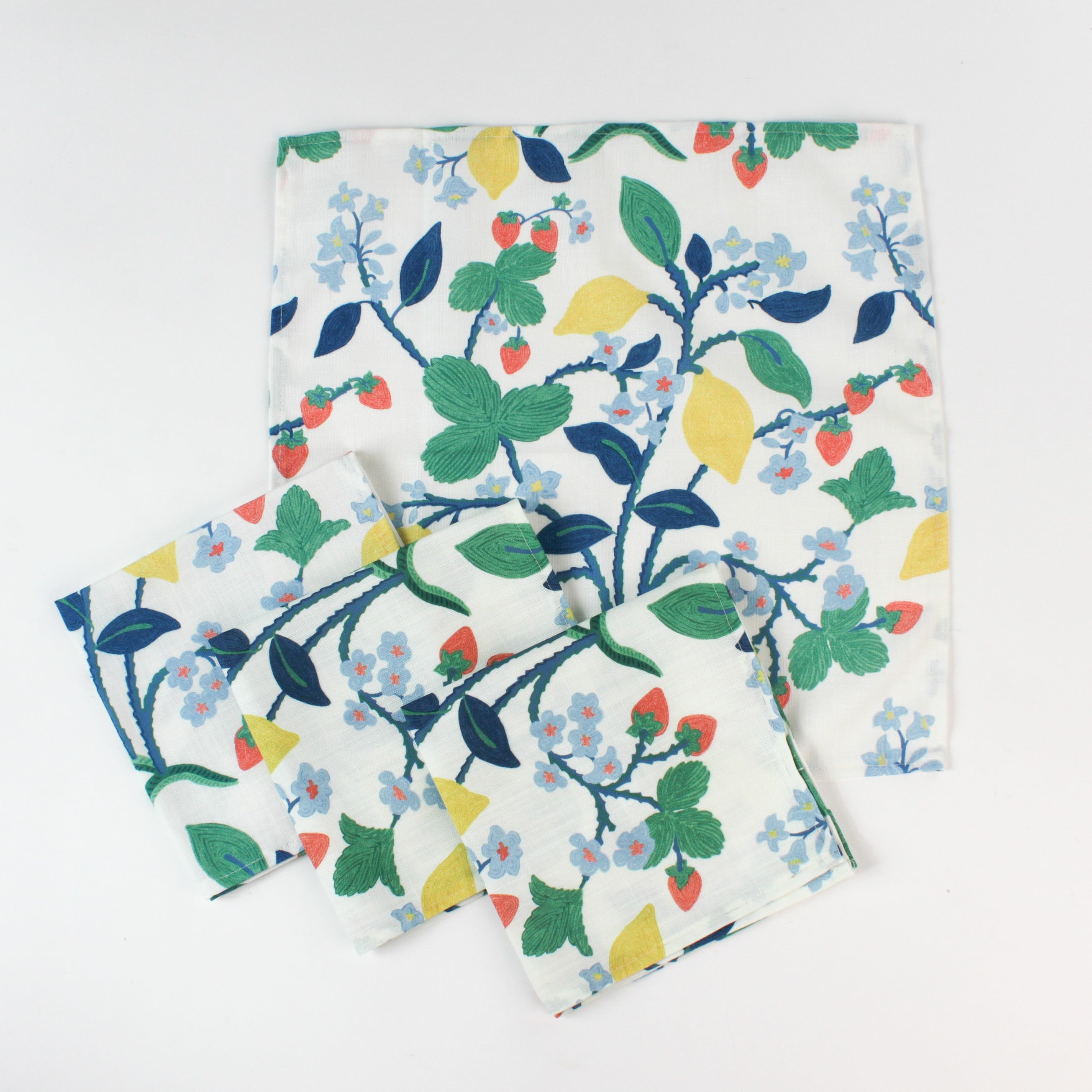 Set of cloth napkins with a colorful botanical print featuring strawberries, lemons, and blue flowers.