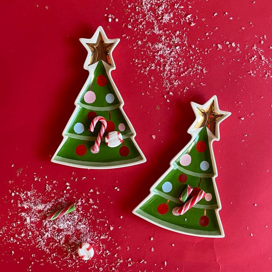 two ceramic green christmas tree accent plates with candy canes and stars on a red background.