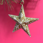 a gold star ornament with white embellishements against a red background