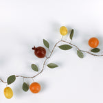 Handcrafted tole metal garland featuring lifelike fruit accents including pomegranate, orange, and lemon with green leaves
